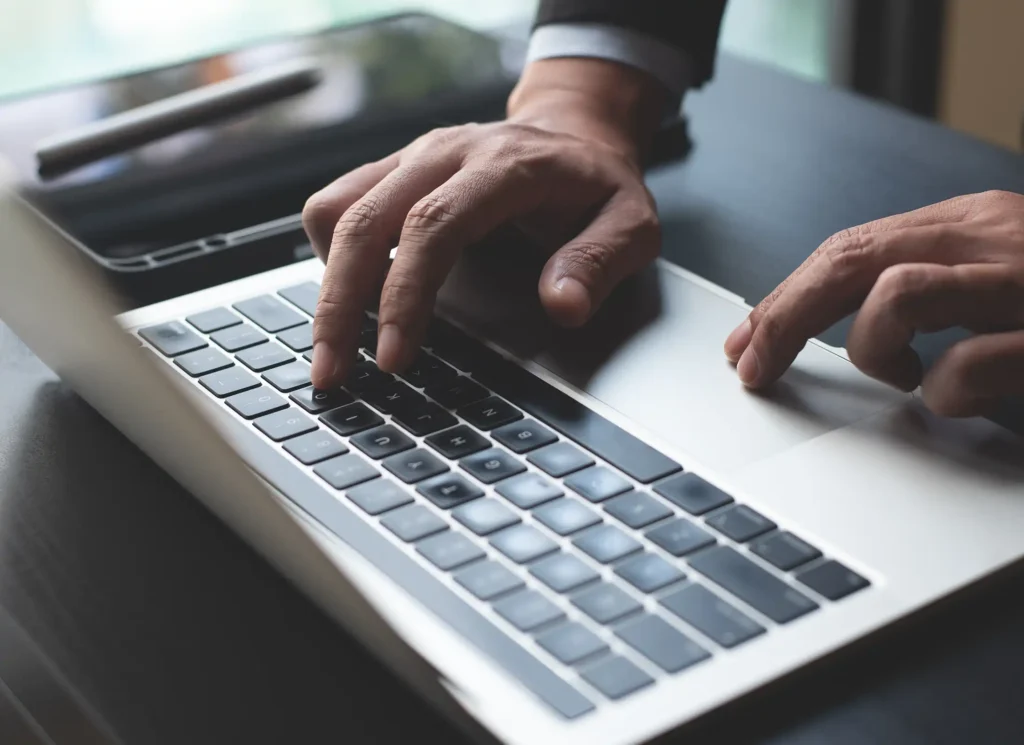 hand typing on laptop computer at office